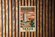 A vintage-style metal sign with the text "AMARILLO TEXAS U.S.A." displayed on it, mounted on a wooden wall.
