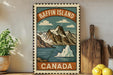 A vintage-style metal sign with a mountain landscape and a polar ice cap, along with the text "Baffin Island, Canada". The sign is displayed on a shelf next to a wooden cutting board and some potted plants.
