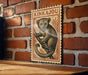 A vintage-style metal sign featuring a cartoon illustration of a kangaroo, mounted on a brick wall.