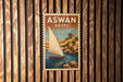 A vintage-style poster of a sailboat on a body of water, with the text "ASWAN EGYPT" prominently displayed.