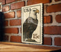A framed image of a bald eagle on a brick wall, with a US postage stamp in the background.