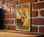 a wooden table with a framed poster of a deer on it, mounted on a brick wall.