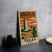 A vintage-style metal sign with a graphic design depicting a tall building and desert landscape, along with the text "AMARILLO TEXAS U.S.A."