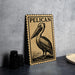 a Pelican postage stamp on a table, with a black and white illustration of the bird.