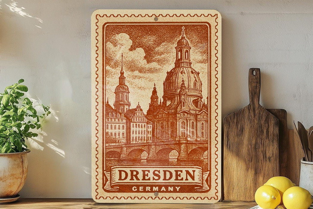 A vintage-style metal sign depicting the Dresden Cathedral in Dresden, Germany, with a wooden cutting board and a potted plant in the foreground.