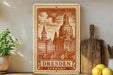 A vintage-style metal sign depicting the Dresden Cathedral in Dresden, Germany, with a wooden cutting board and a potted plant in the foreground.