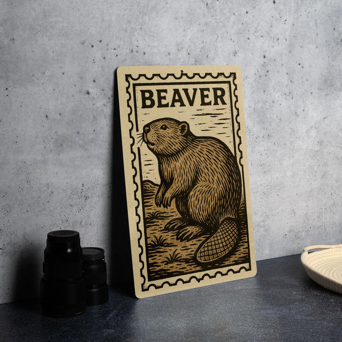 A wooden postcard featuring a beaver illustration is displayed on a table.