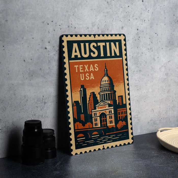 A vintage-style metal sign with the text "AUSTIN TEXAS USA" and an illustration of the Texas State Capitol building, placed on a gray countertop next to some black camera lenses.