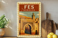 a vintage-style poster of the Fes, a famous landmark in Morocco, displayed on a wall next to a wooden cutting board and some potted plants.