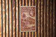 A vintage postage stamp from Victoria Seychelles, featuring a tropical landscape with palm trees and a mountain in the background.