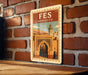 A vintage-style poster of the Fes, or medina, in Morocco, displayed on a brick wall.
