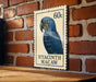 A postage stamp featuring a blue parrot, specifically a hyacinth macaw, is displayed on a brick wall.