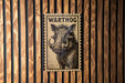 A vintage warthog postage stamp is displayed on a wooden wall.