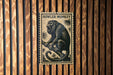A framed image of a howler monkey is displayed on a wooden wall.