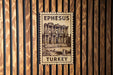 A wooden wall with a framed image of the ancient city of Ephesus, Turkey, mounted on it.