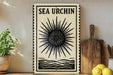 a decorative sign with a sunburst design, placed on a wooden surface next to a wooden cutting board and some lemons.