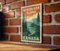 A vintage-style postage stamp depicting Vancouver Island, Canada, with a scenic landscape of pine trees, mountains, and a body of water.