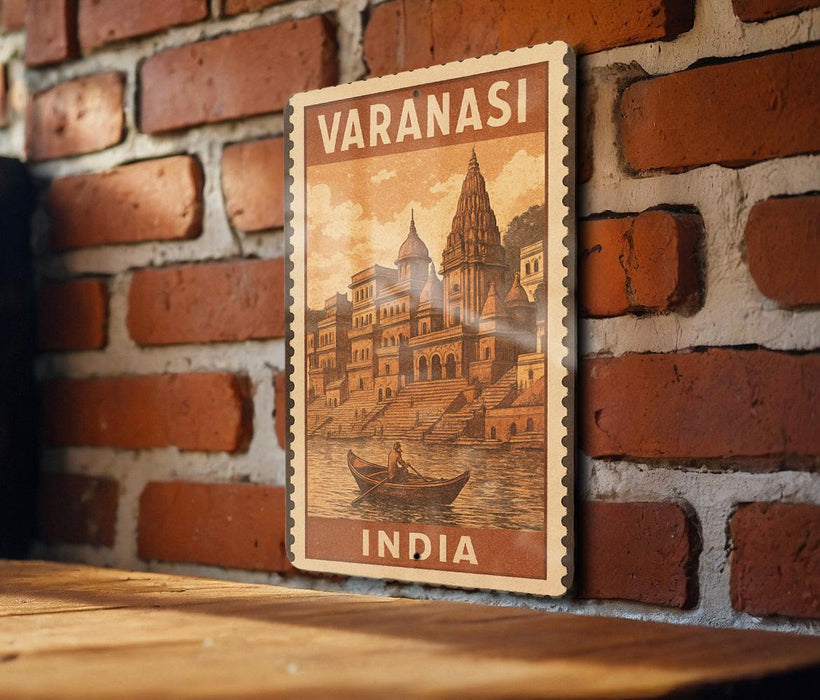 A vintage-style poster of Varanasi, India, featuring a temple and a boat on a river, is displayed on a brick wall.
