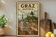 A vintage-style postage stamp depicting the town of Graz, Austria, with a church spire and other buildings in the background.
