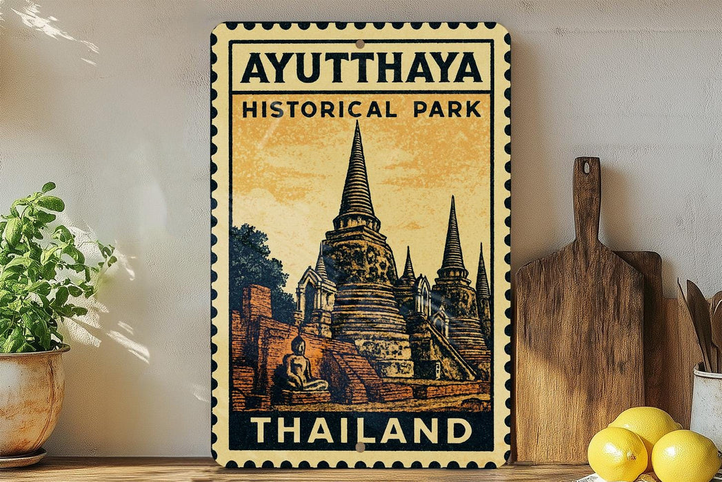 a vintage-style stamp or sign with the text "AYUTTHAYA HISTORICAL PARK THAILAND" and an illustration of a temple or pagoda. The sign is displayed on a shelf, with a potted plant to the left and a wooden cutting board to the right.