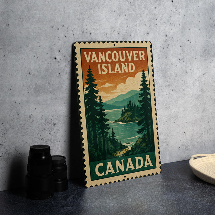 A vintage-style metal sign with the text "VANCOUVER ISLAND CANADA" printed on it, depicting a scenic landscape with pine trees and a body of water.