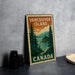 A vintage-style metal sign with the text "VANCOUVER ISLAND CANADA" printed on it, depicting a scenic landscape with pine trees and a body of water.