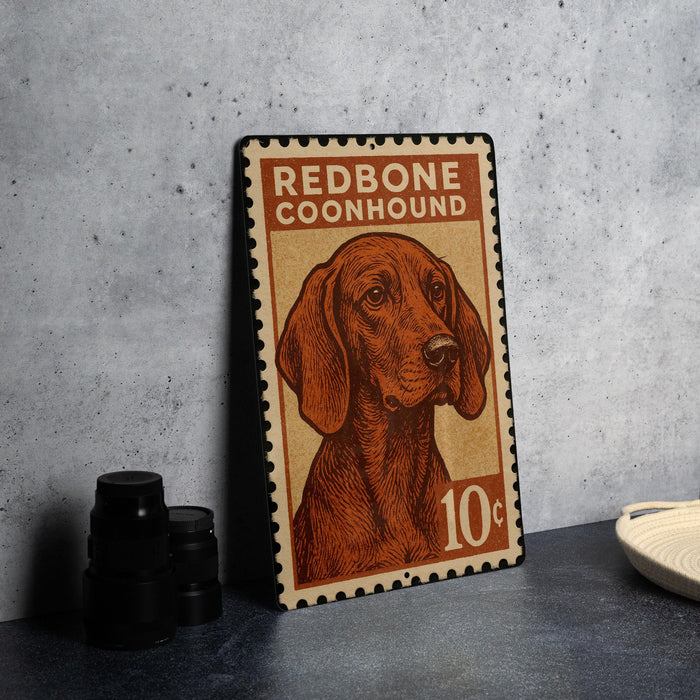 A metal sign featuring a redbone coonhound dog, with a stamp-like border and text indicating the dog's breed.