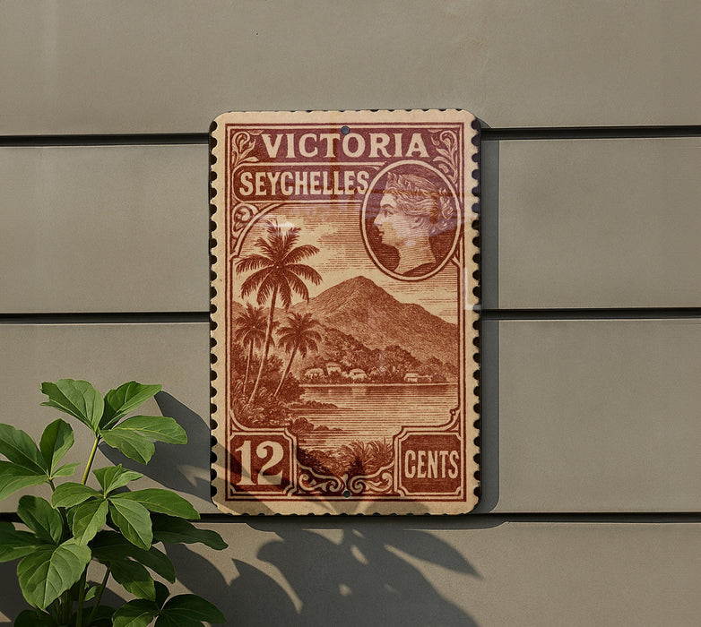A vintage Victoria Seychelles postage stamp is displayed on a wall, featuring a tropical landscape with palm trees and mountains.