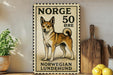 A vintage Norwegian Lundehund dog stamp is displayed on a wall, with a wooden cutting board and a potted plant to the side.