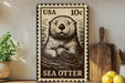 A metal stamp featuring a sea otter, with the text "USA 10¢" printed on it. The stamp is placed on a wooden surface, with a potted plant, a wooden cutting board, and some lemons nearby.
