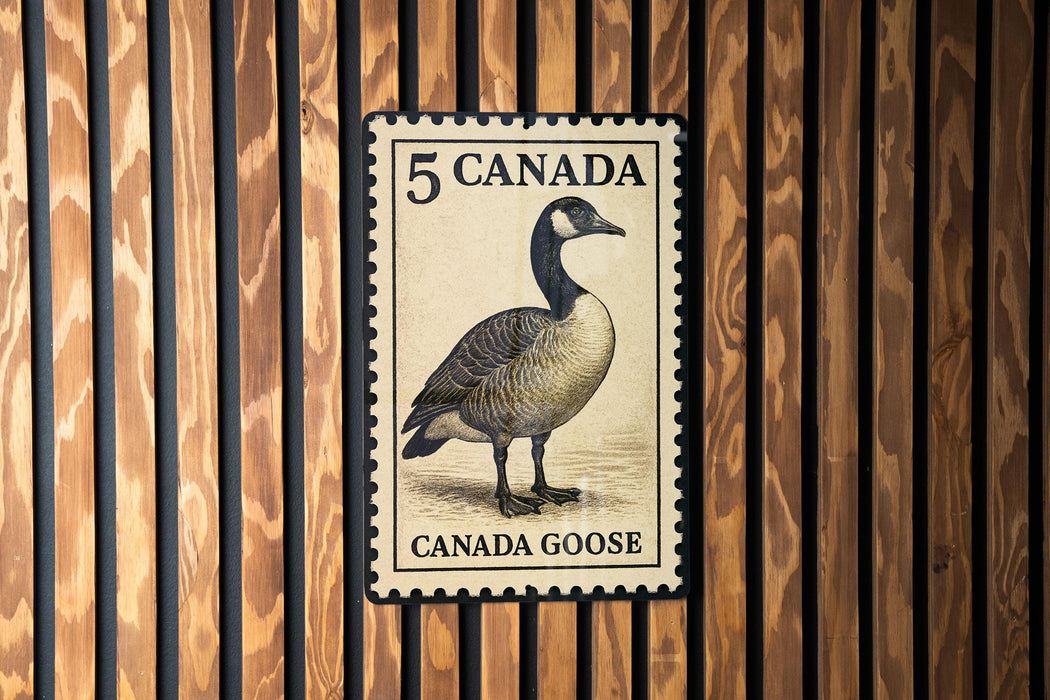 A 5 Canada goose postage stamp is displayed on a wooden wall.