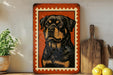 a framed illustration of a Rottweiler dog, which is a large black and tan breed of dog. The dog is depicted in a close-up portrait, with a detailed and realistic illustration. The framed artwork is placed on a shelf, surrounded by various kitchen utensils and items, such as a wooden cutting board, a knife, and a bowl.