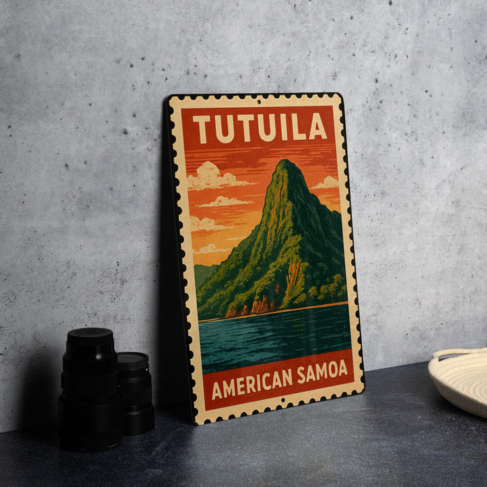 A vintage-style metal sign with the text "TUTUILA AMERICAN SAMOA" and an illustration of a mountain landscape with a body of water.