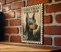 A wooden table with a framed image of a Doberman Pinscher dog on it, mounted on a brick wall.