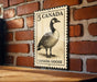 A metal sign featuring a Canadian goose on a brick wall.