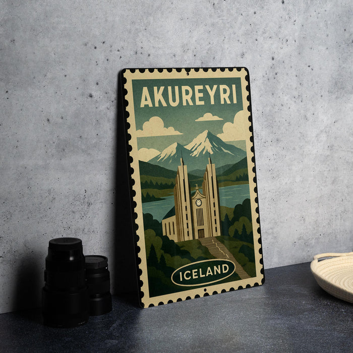 A metal sign with a vintage-style illustration of a castle and mountains, along with the text "AKUREYRI ICELAND", is displayed on a table.