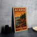 A vintage-style metal sign for Acadia National Park in the United States, featuring a scenic landscape with pine trees, rocky cliffs, and a body of water.