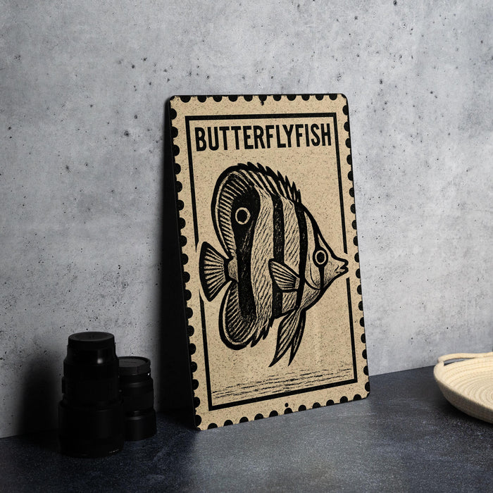 a framed print of a butterflyfish on a wall, with a stack of black camera lenses and a woven basket visible in the foreground.