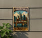 A framed poster of the city of Frankfurt, Germany, featuring a colorful illustration of the cityscape and a bridge.