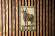 a metal sign with an illustration of a horned animal, likely a gazelle or similar species, mounted on a wooden wall.