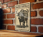 A sign with the word "WATER" and an illustration of a buffalo is mounted on a brick wall.