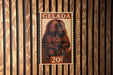 A postage stamp featuring a monkey is displayed on a wooden wall.