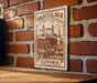 A wooden surface with a framed illustration of a castle and buildings, mounted on a brick wall.