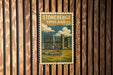 A vintage-style postage stamp depicting Stonehenge, a famous monument in England, is displayed on a wooden wall.