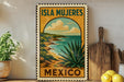 A vintage-style metal sign with the text "ISLA MUEJERES MEXICO" and an illustration of a desert landscape with a cactus plant, all set against a white wall.