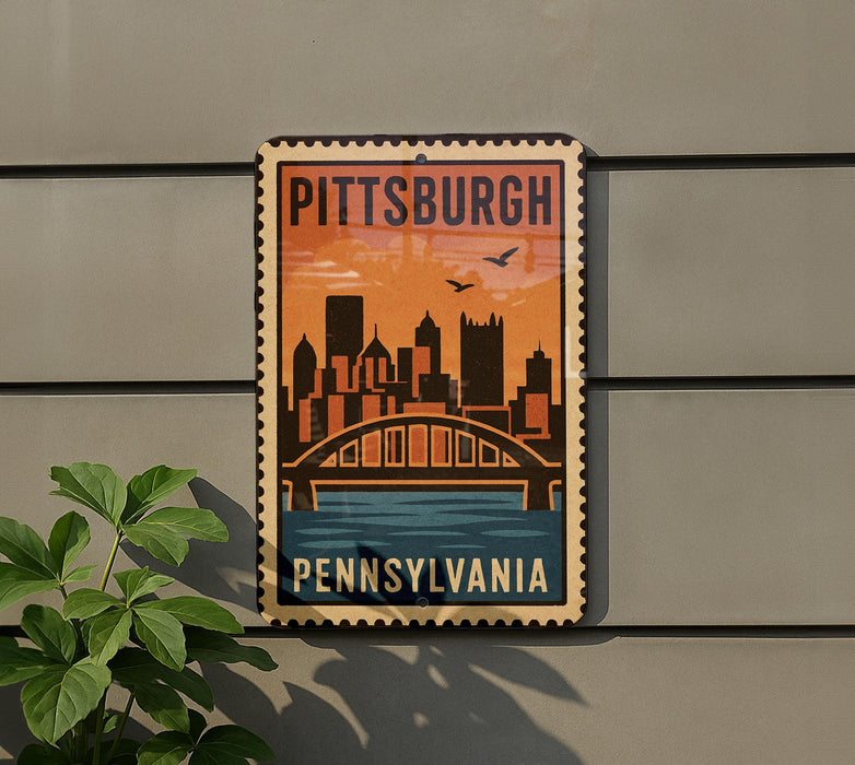A vintage-style metal sign with the text "PITTSBURGH PENNSYLVANIA" and an illustration of a city skyline with a bridge.