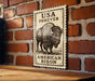 a wooden table with a framed poster of a buffalo on it, mounted on a brick wall.