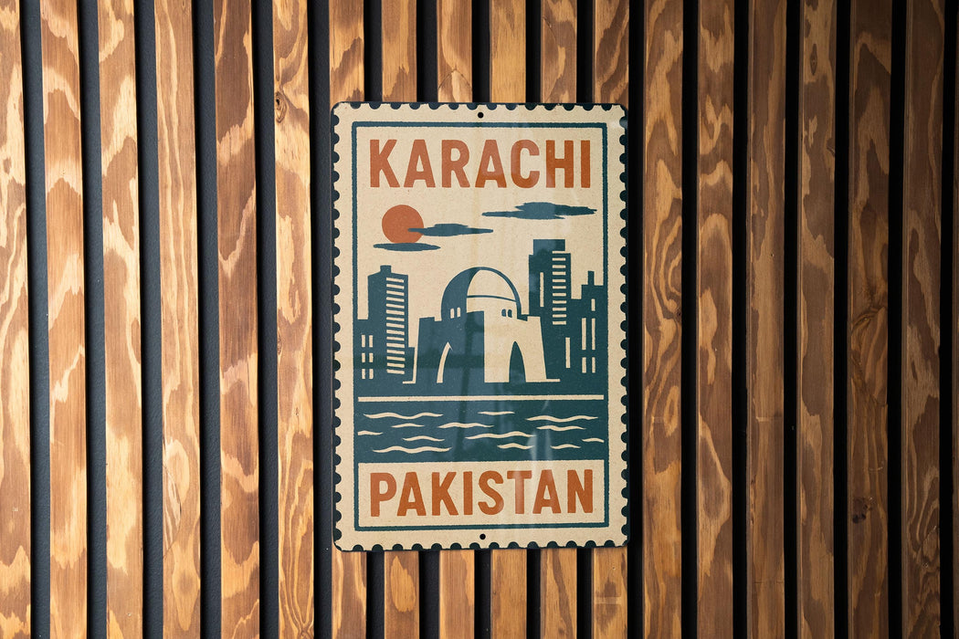 A vintage-style metal sign with the text "KARACHI PAKISTAN" displayed on a wooden wall.