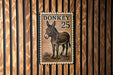a donkey stamp with the number 25 on it, mounted on a wooden wall.
