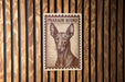 A brown and white illustration of a dog, specifically a pharaoh hound, is displayed on a wooden surface.